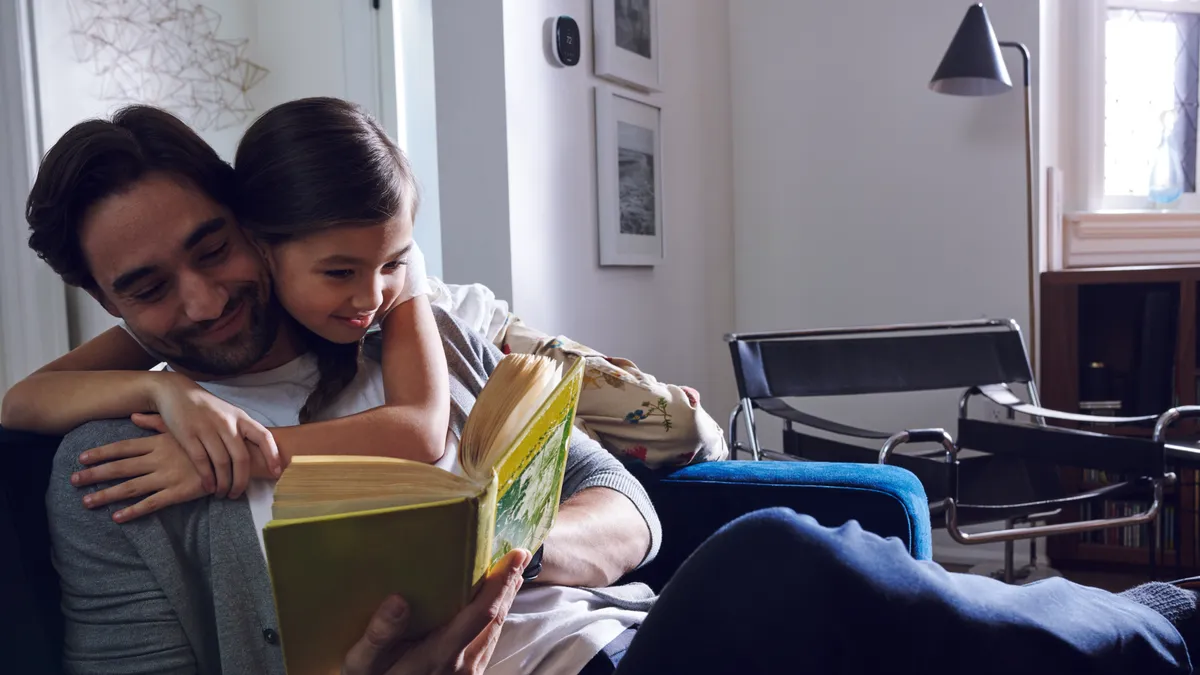 Child hugging man while he reads a book