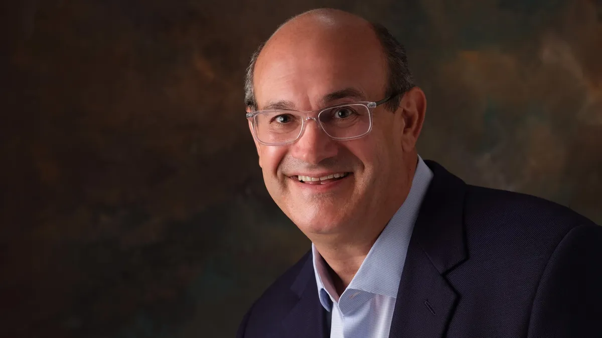 An image of Michael Casey, chief development officer at SPB Hospitality. He is wearing a suit in front of a brown background.