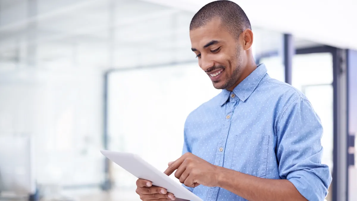 A young business professionals looks at a digital tablet in a modern office.