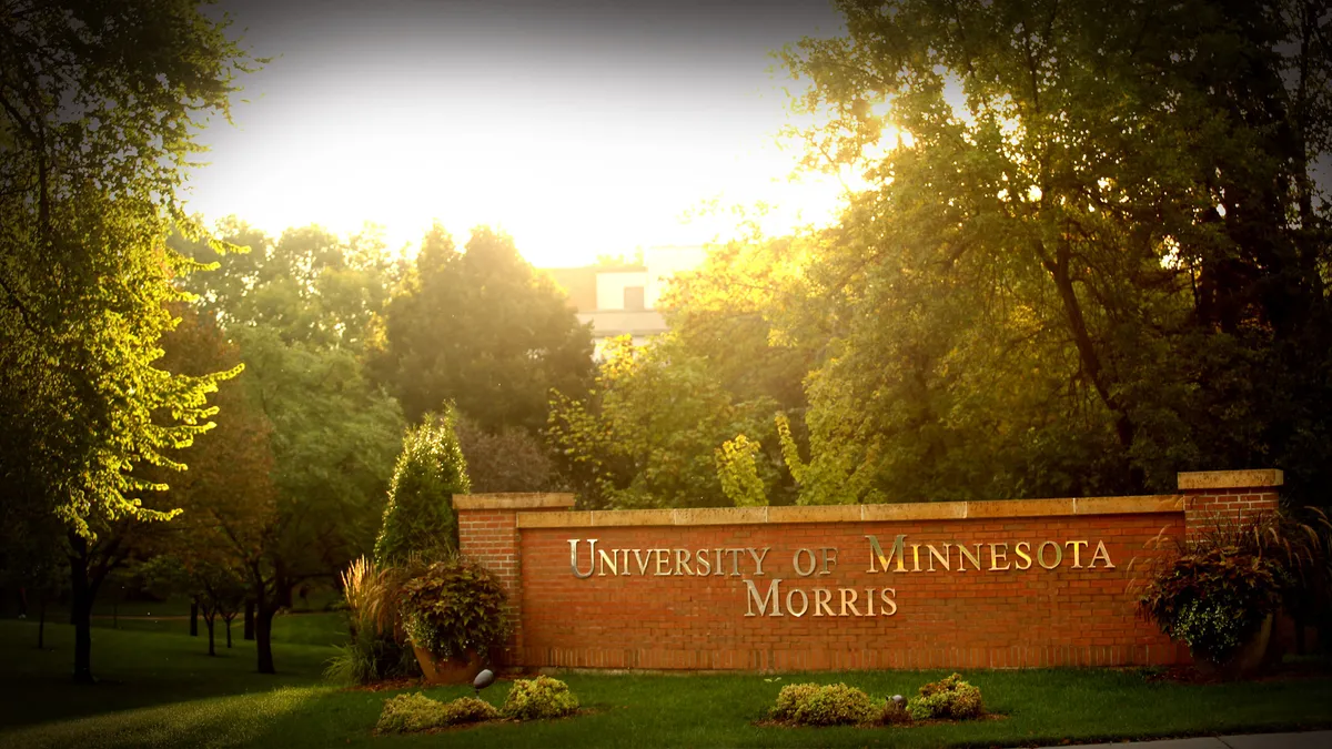 A campus entryway with a large brick sign that reads "University of Minnesota Morris"