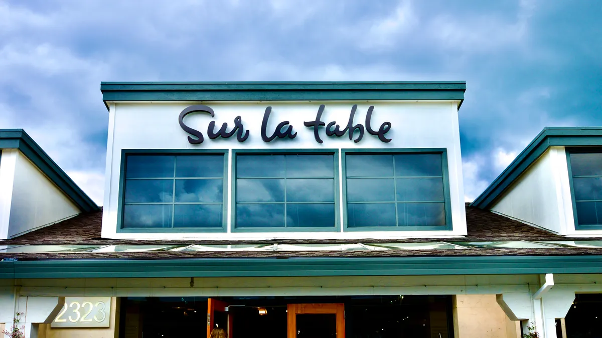 Clouds build behind a dormer window that reads "Sur La Table."