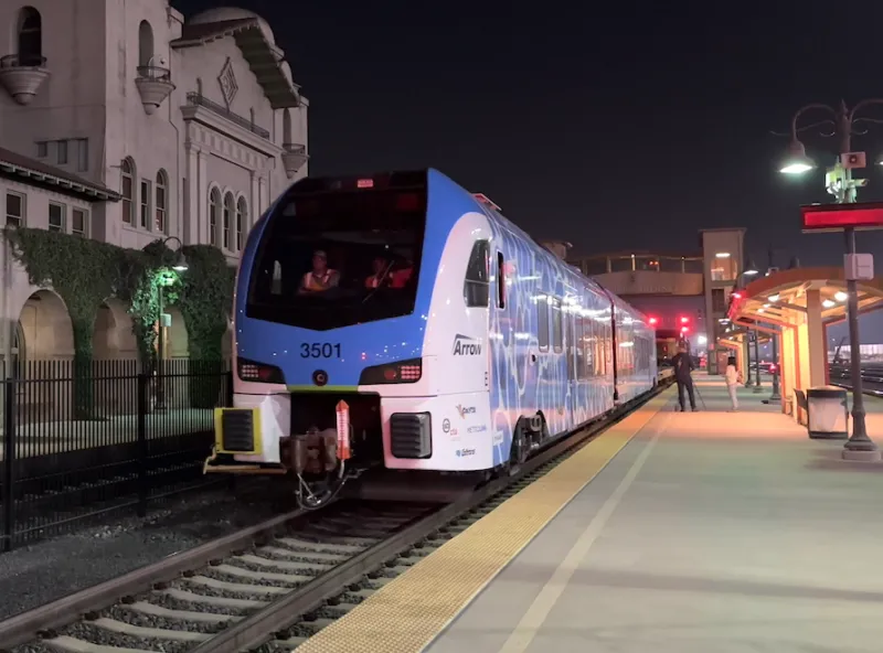 A modern blue and white train at a station at night.