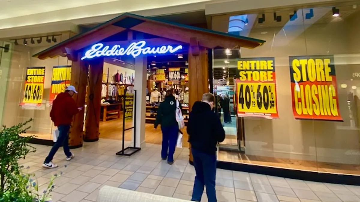 People walking into an Eddie Bauer that is going out of business.