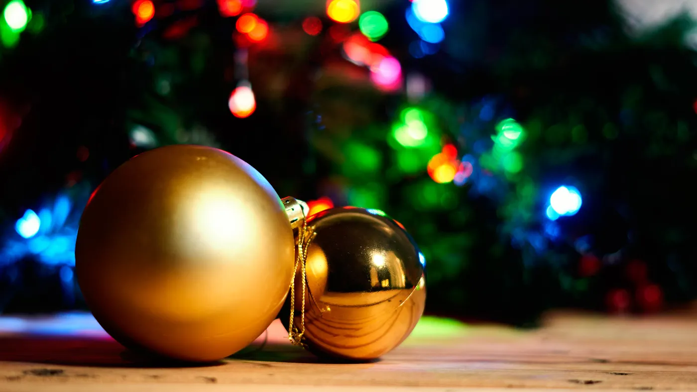 Two golden Christmas tree balls on wood.