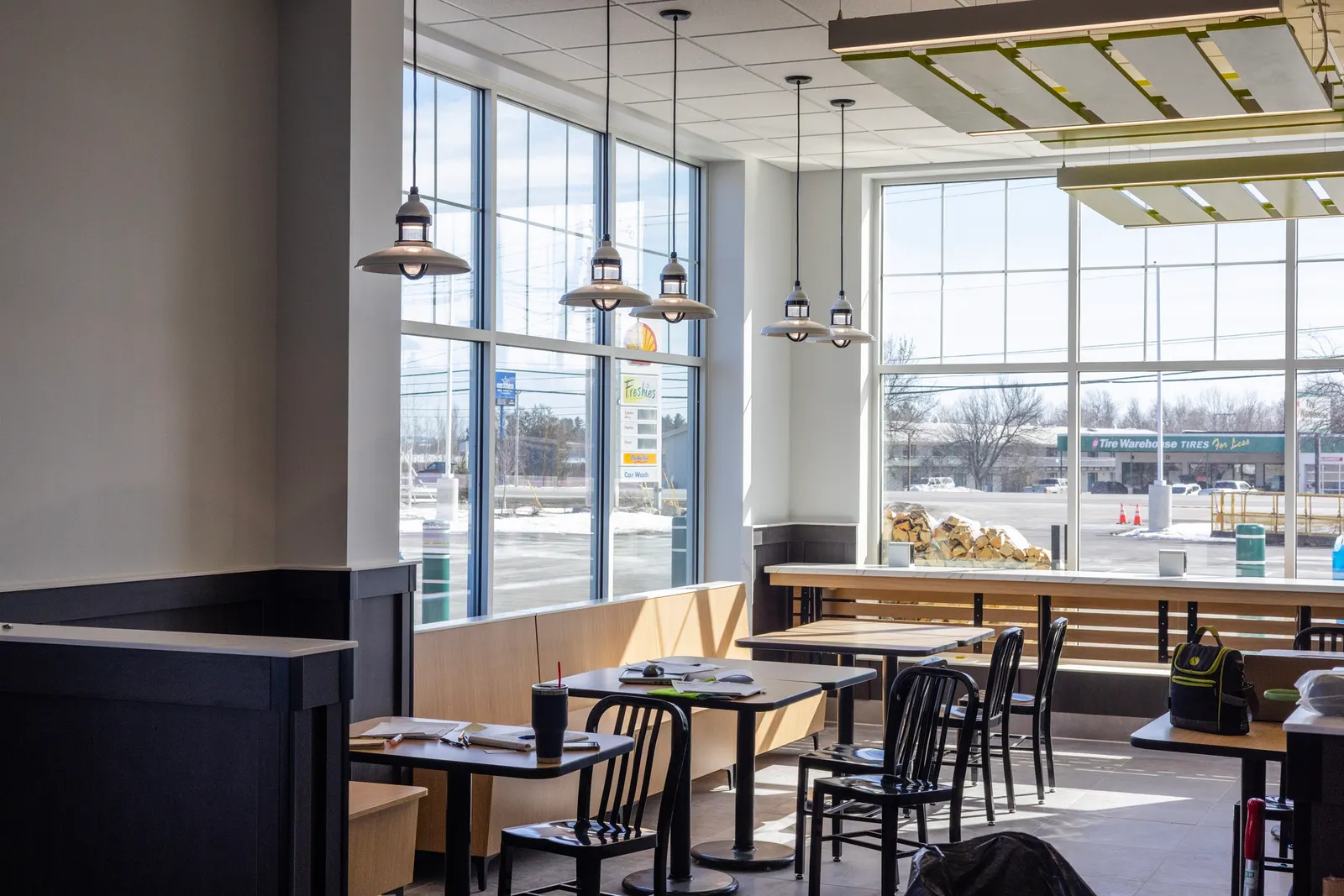 A photo of a seating area inside a store, containing multiple chairs and tables, with the parking lot visible through the windows.