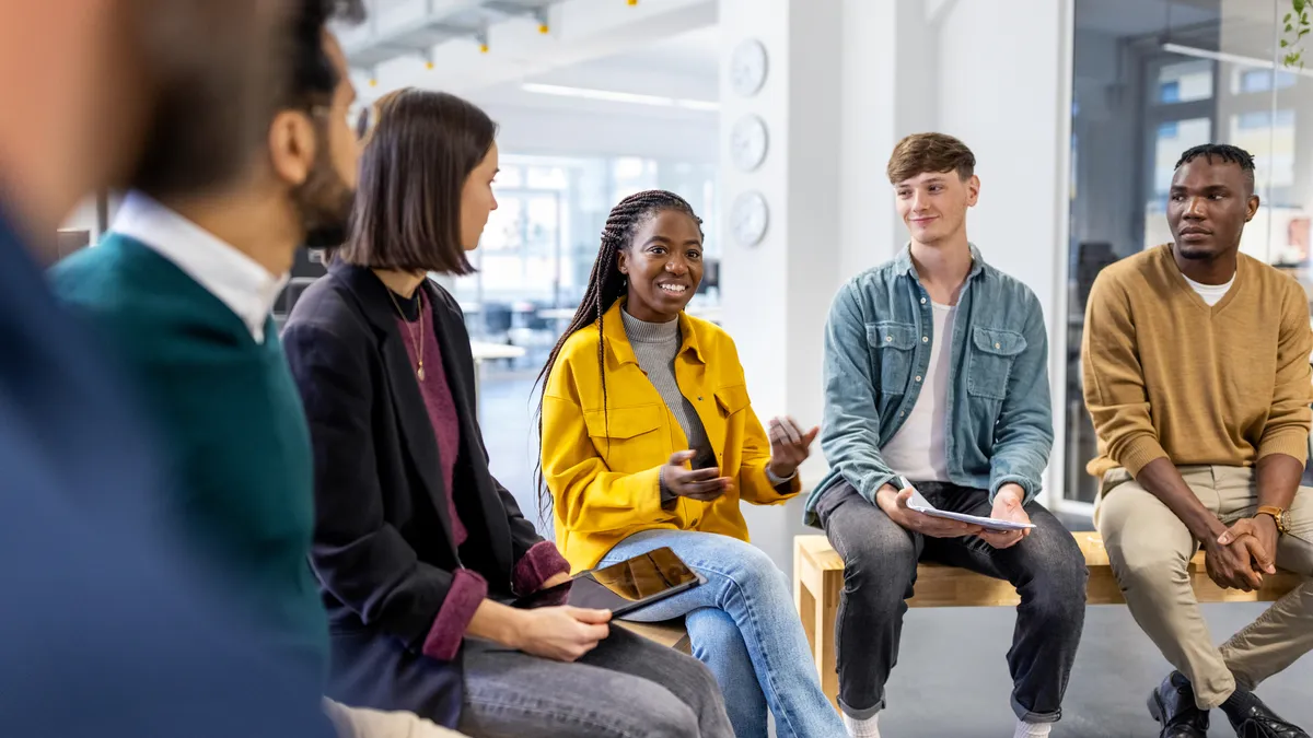 Office worker talking with colleagues sitting in circle at a coworking office.