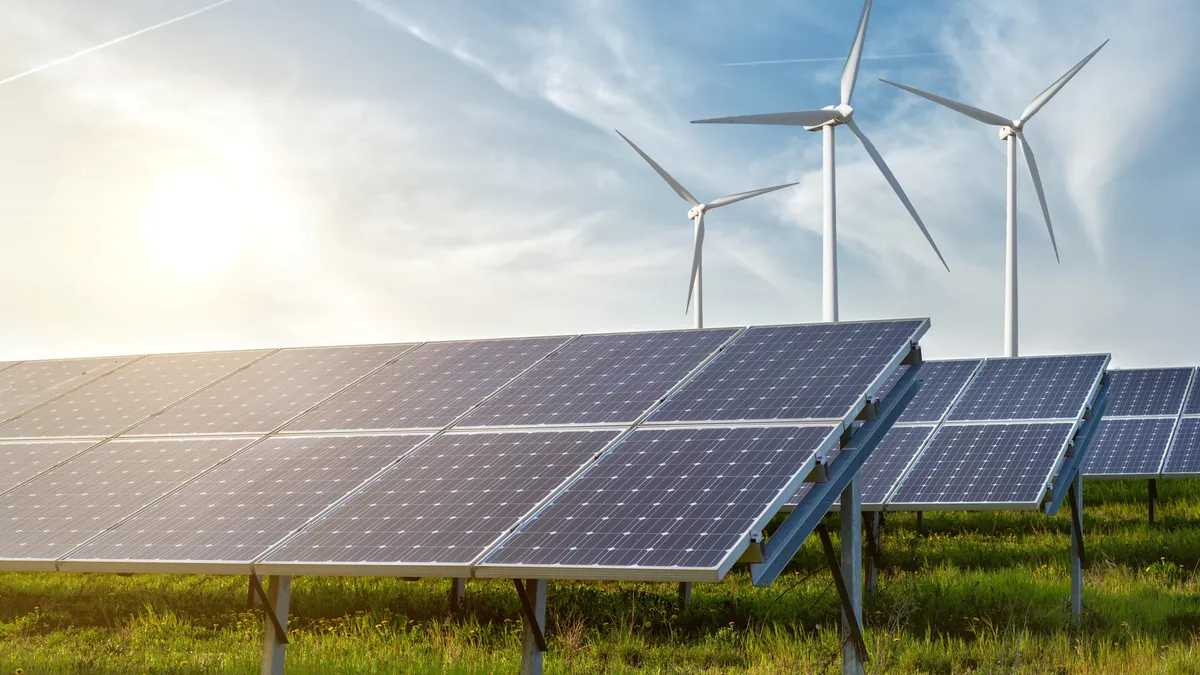 Solar panels and wind generators under blue sky on sunset