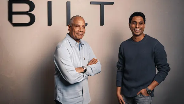 Ken Chenault and Ankur Jain stand in front of a sign that says "Bilt."