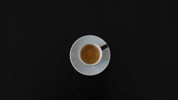 a white cup of expresso on a black background
