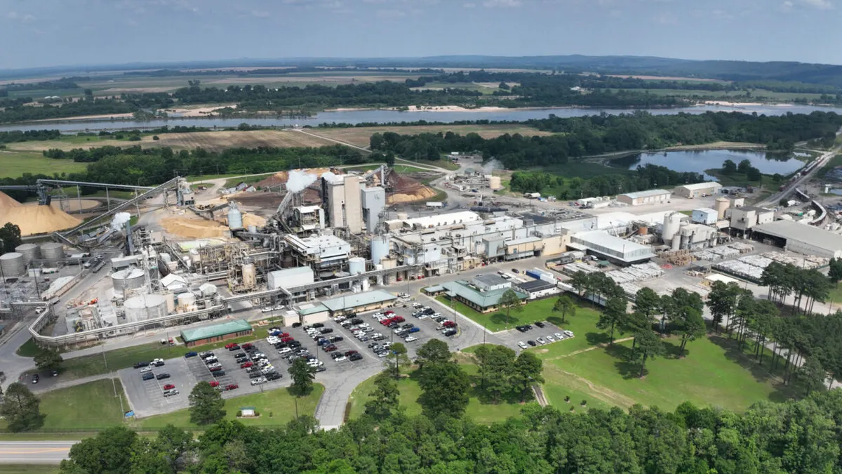 Aerial view of an industrial facility near trees and a waterway.