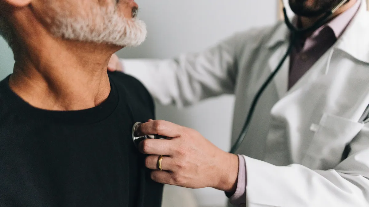 A closeup of a doctor examining a patient using a stethoscope.