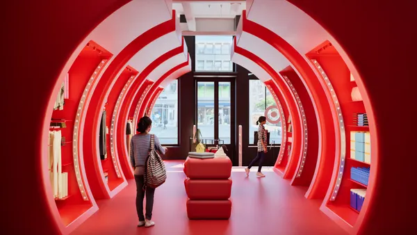 People walk through a red tunnel in a store.