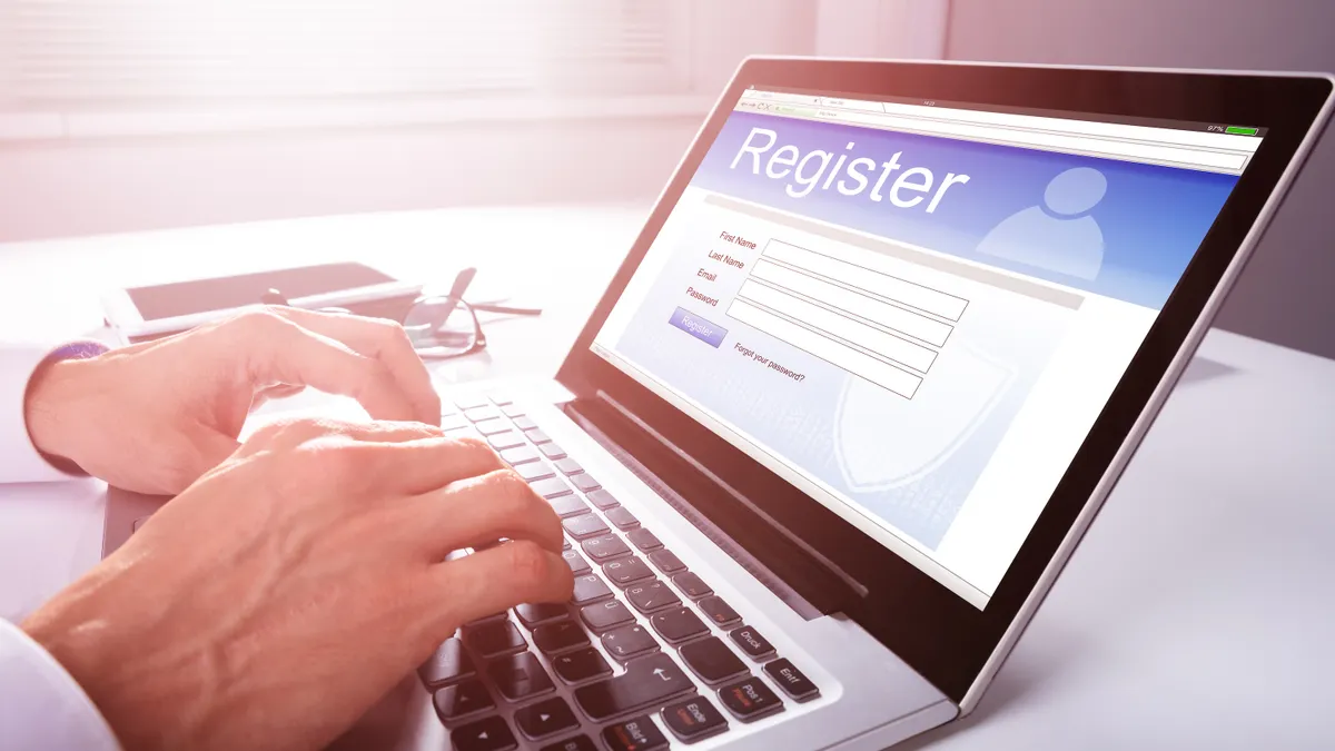 A person fills out an online registration form using a laptop computer.