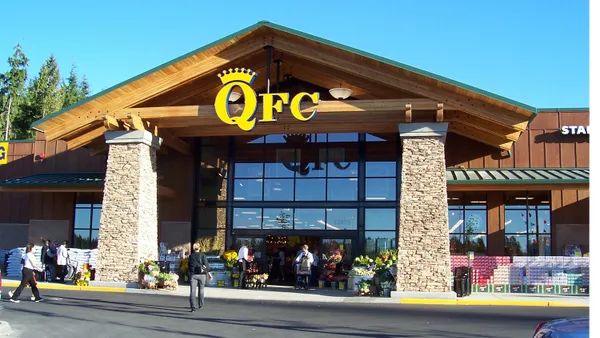 Exterior of a supermarket with a yellow "QFC" sign in front of a blue sky