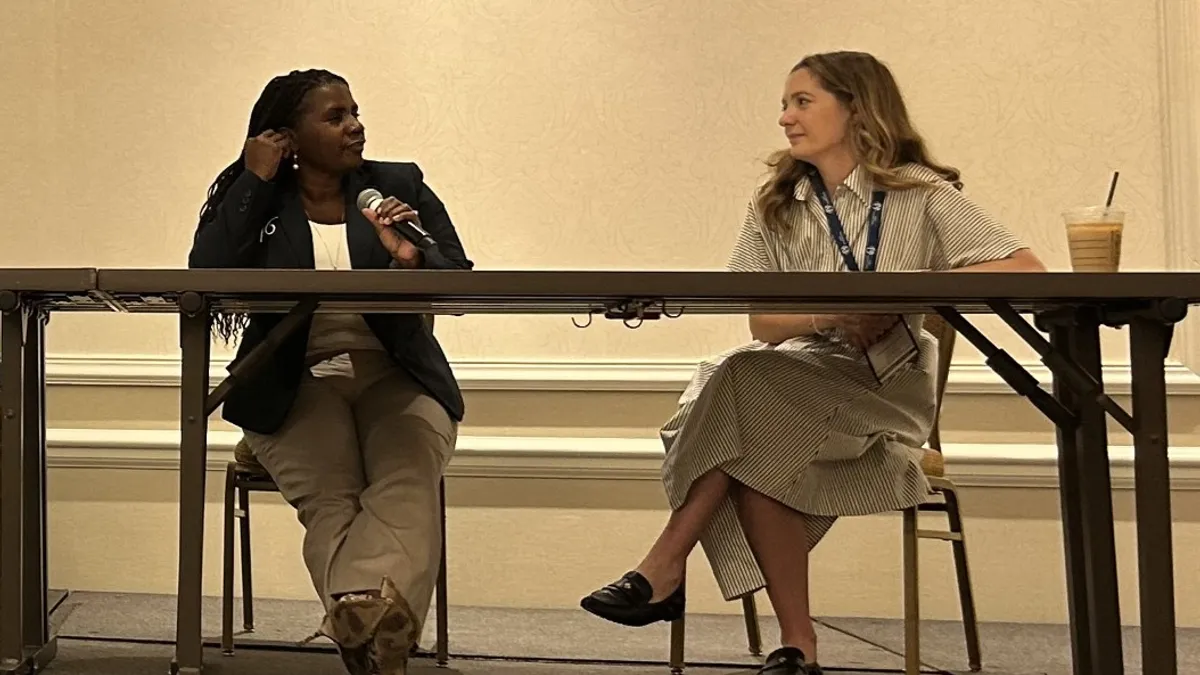 Two speakers at the Association of School Business Officials International annual conference sit at a table discussing the rising cost of special education in public schools.