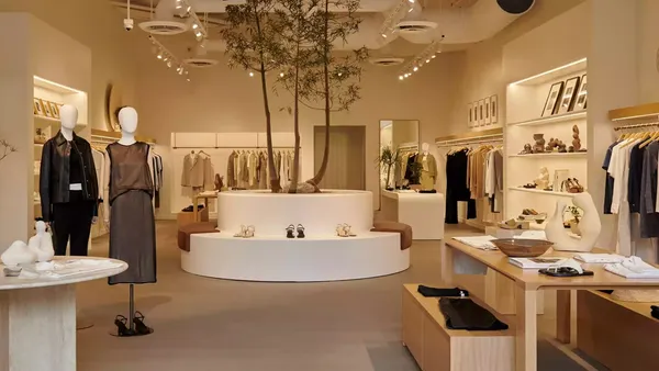A interior of a clothing store shoes mannequins wearing women's clothing against neutral-colored walls