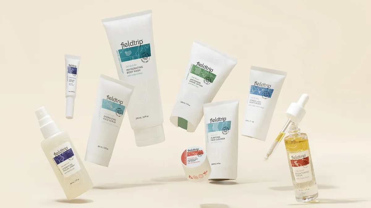 A grouping of Fieldtrip skincare products in white containers with colorful labels, all on a cream-colored background.