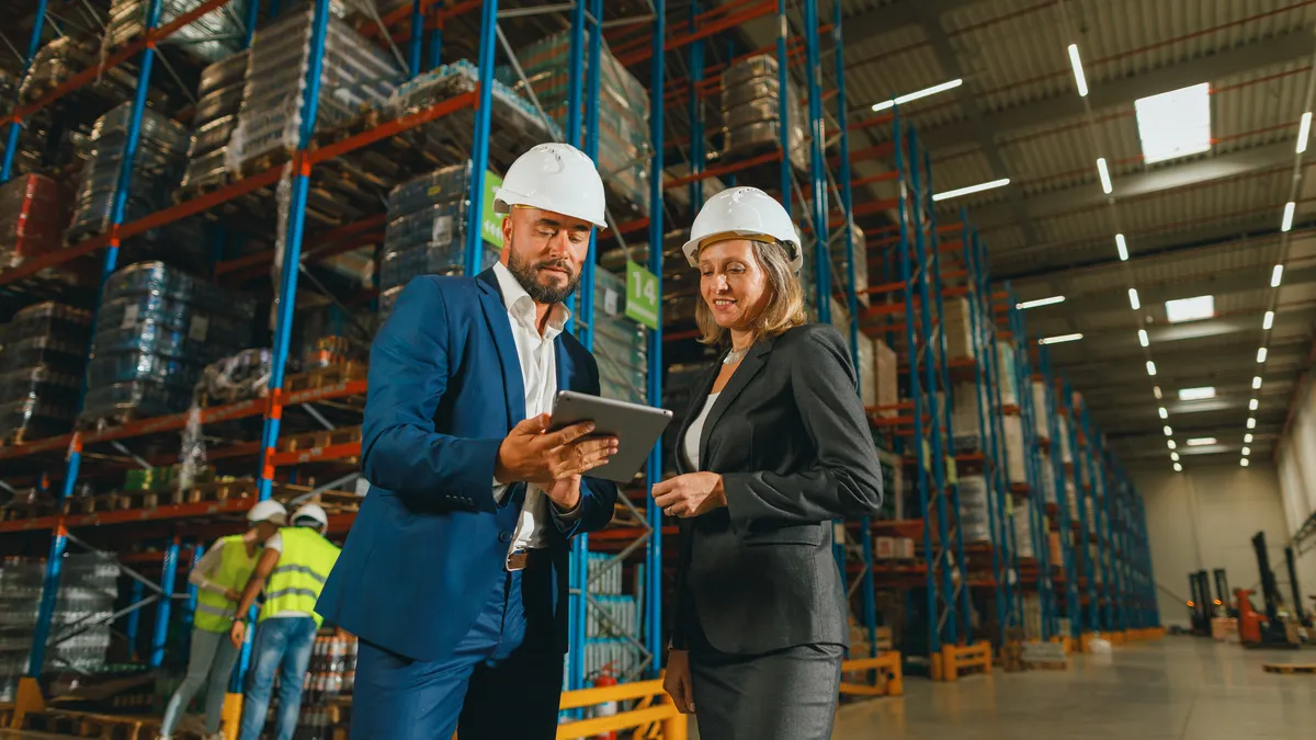 A businessman and a businesswoman discussing work in the warehouse using a digital tablet