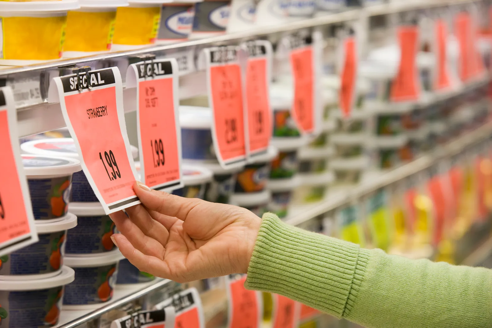 Hand reaching out to "Special" pricing tag in a grocery store.