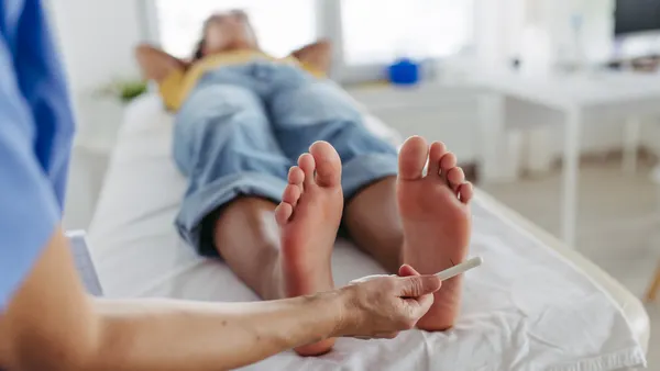 A diabetologist tests for loss of sensation in a patient's feet.