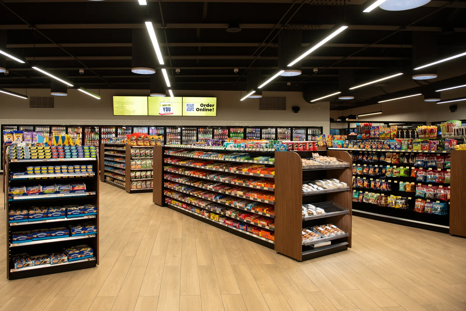 A photo of the itnerior of a convenience store, showing shelves of snacks and beverage coolers.