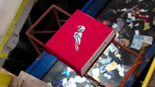 An electronic device positioned over collected recyclable materials on a conveyor belt.
