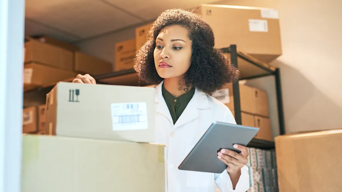 Shot of a young woman using a digital tablet while doing inventory in the storeroom of a pharmacy