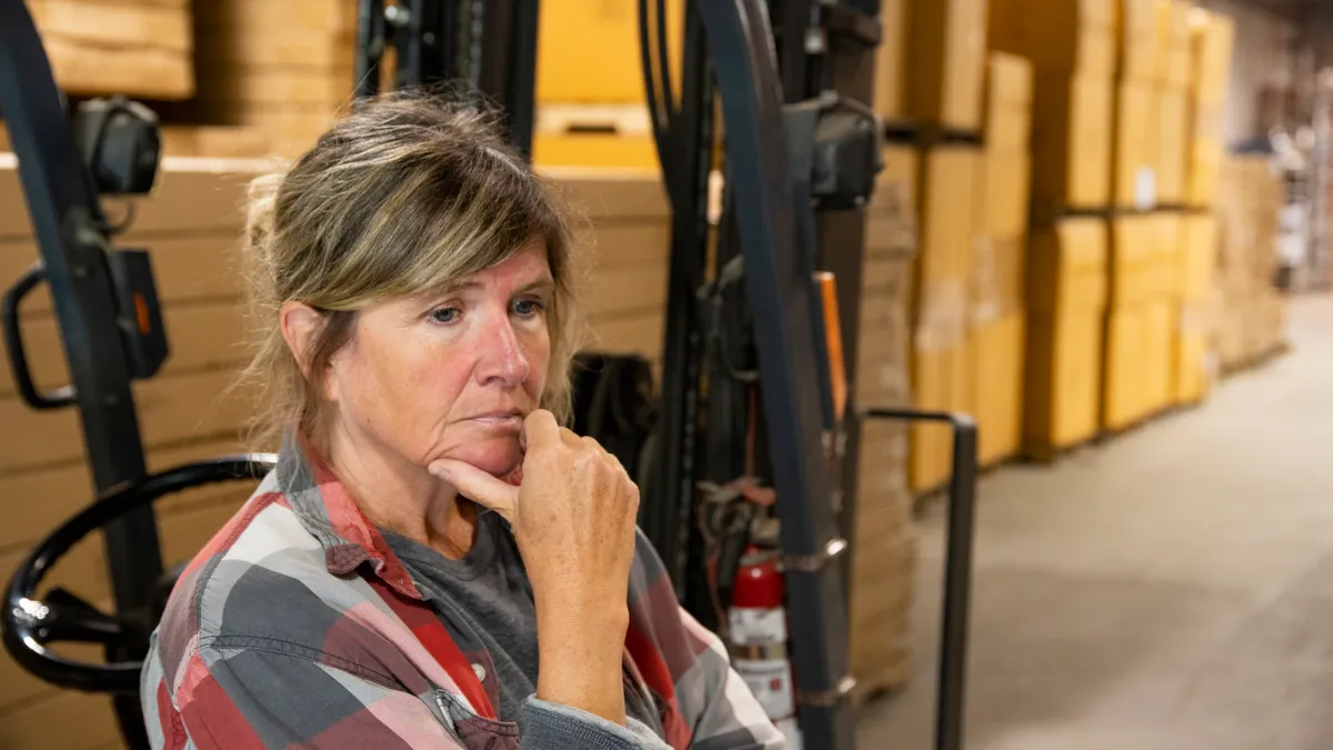 Female employee looking sad in a warehouse