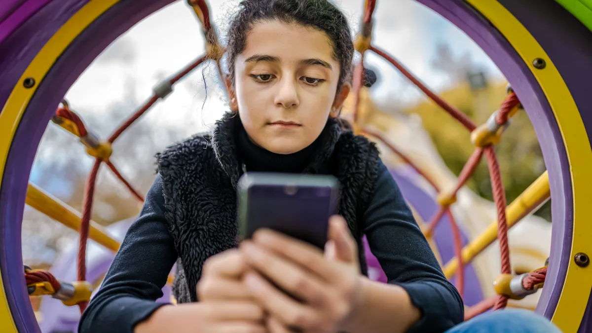 Little girl playing on mobile phone instead of enjoying the Park