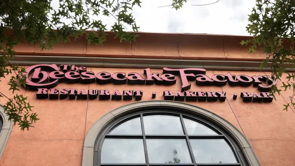 Cheesecake Factory signage hangs on the side of a restaurant.