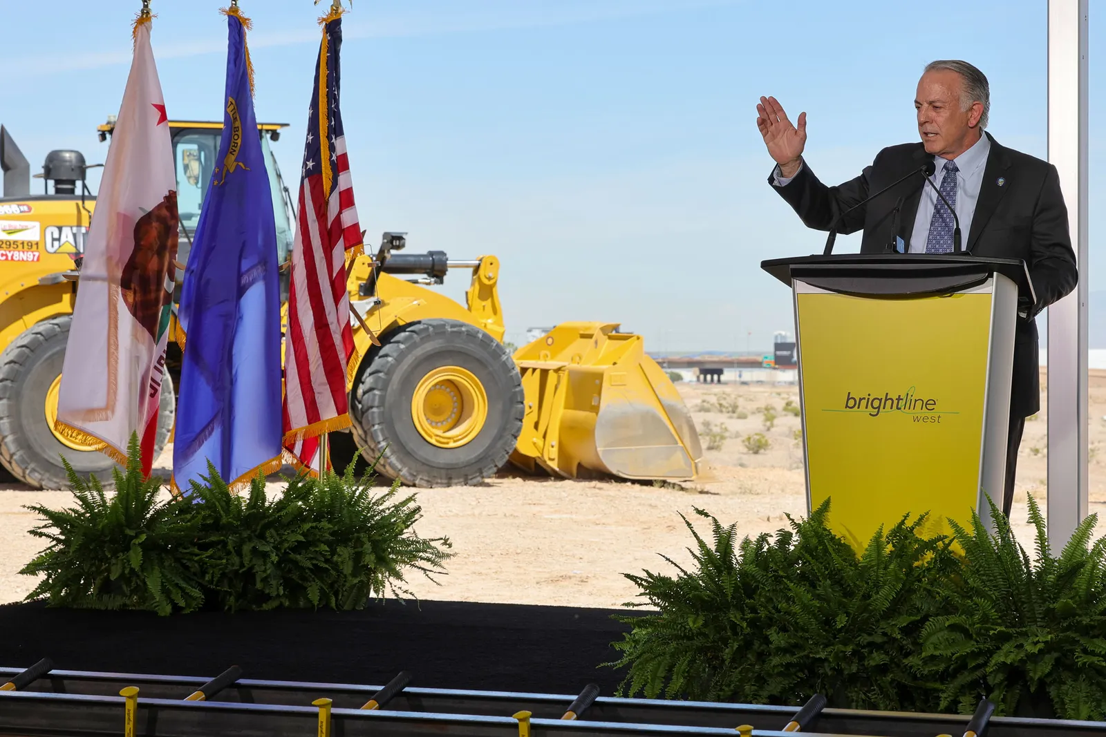 Man in suit at podium on a construction site.