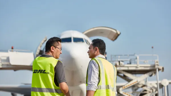 Two people in yellow high visibility vests stand in front of a freighter aircraft