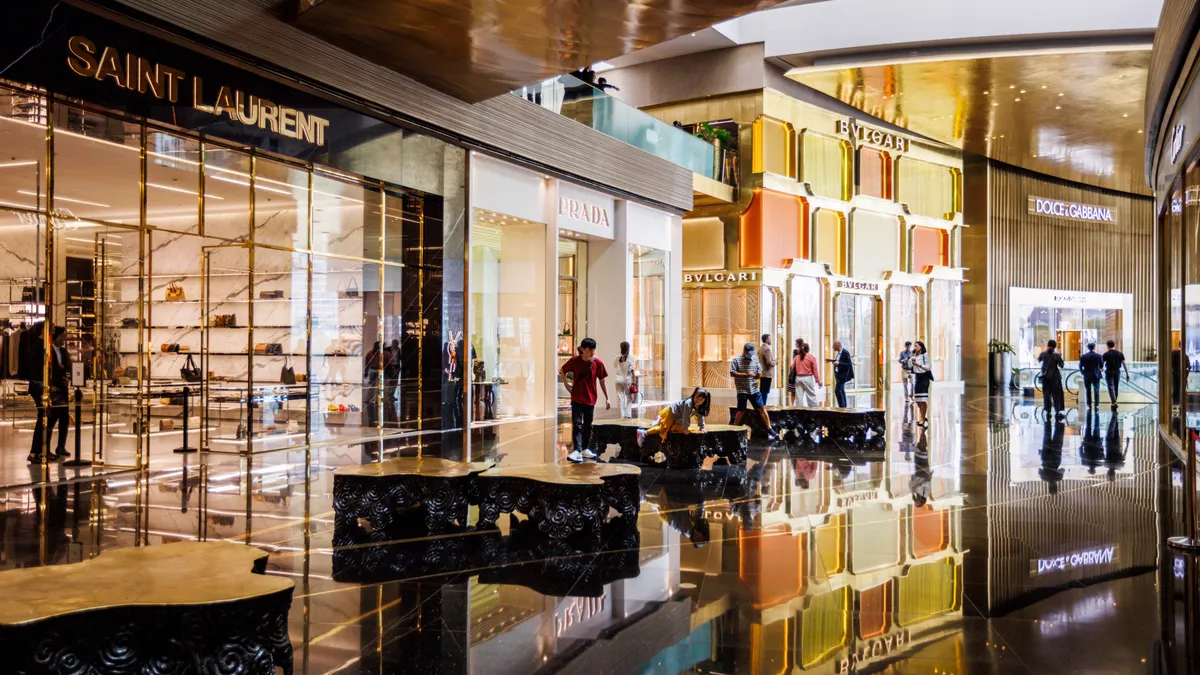 A gold mall interior features many high-end luxury storefronts.