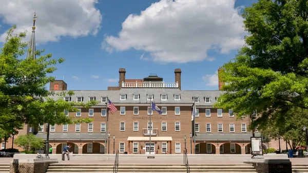 The front of a large brick building with flags in front of it.