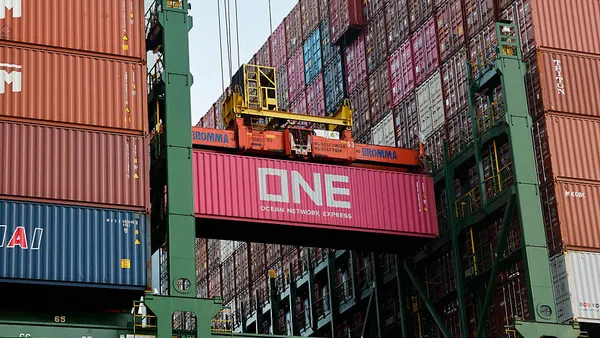 A shipping container is loaded onto an ocean vessel at a water port.
