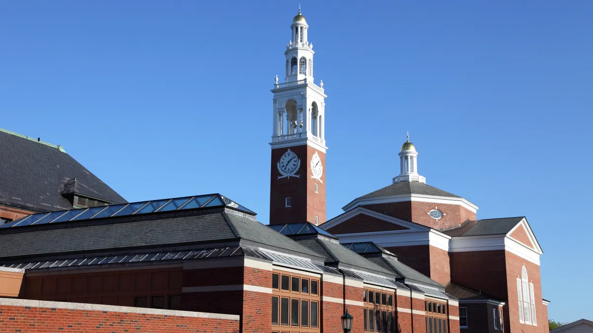 An old-fashioned brick academic building with a clock tower set against a blue sky.