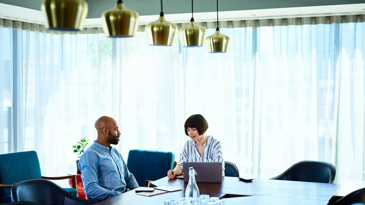 Two people are sitting in a conference room talking