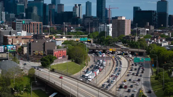 Overhead view of bumper-to-bumper traffic on a highway leading to the tall buildings of Chicago in the background.