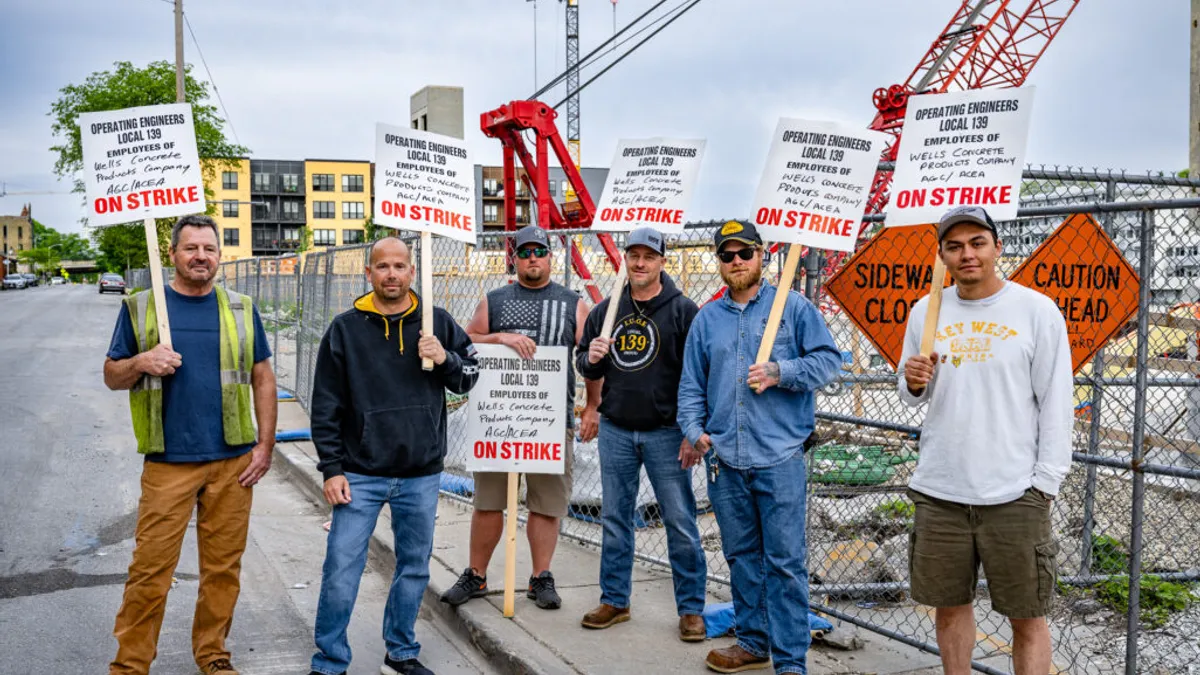 A group of people on strike pose with protest signs.