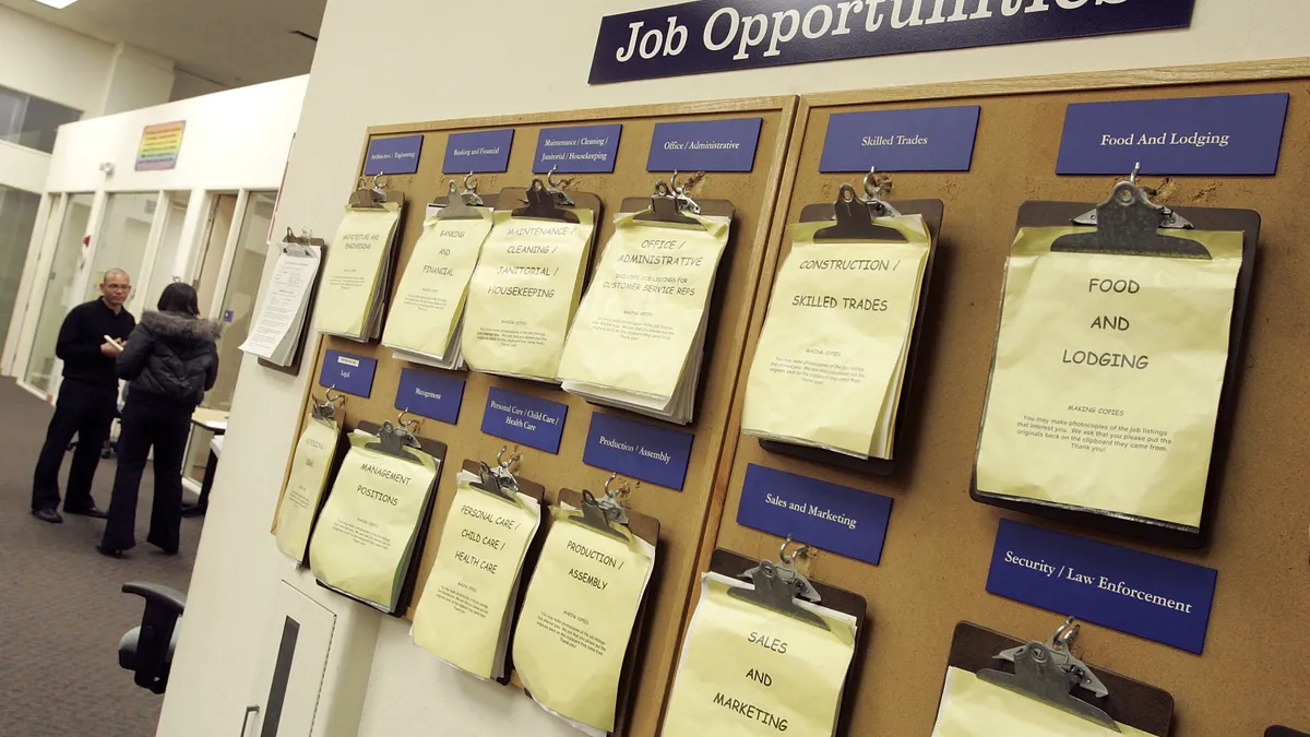 A cork board displays a list of job postings for various departments.