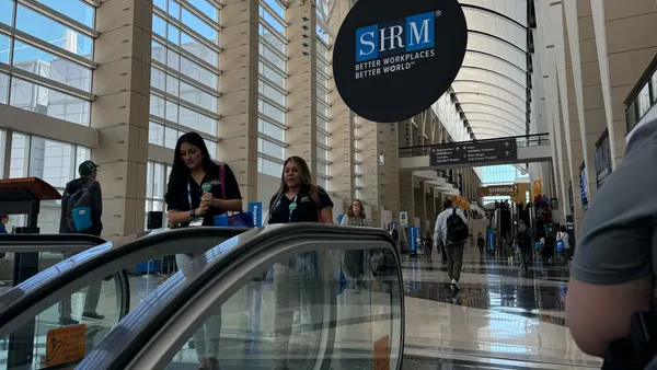 Individuals walk through a conference hall below a SHRM sign.