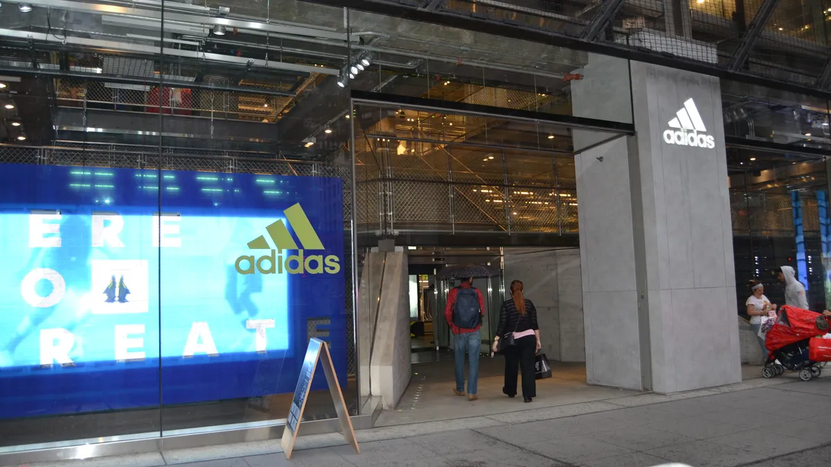 A storefront with a blue screen seen through glass, with an Adidas logo on it.