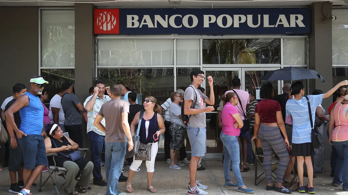 people stand in line outside of banco popular in puerto rico.