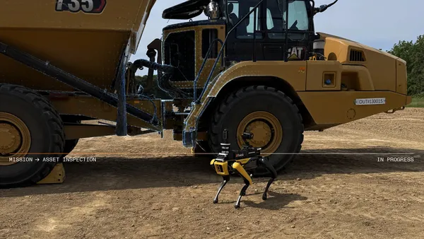 An image of a small quadripedal robot with a large yellow machine behind it with the word "CAT" on it.