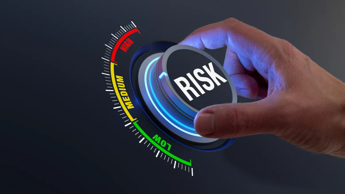 Image shows a hand on a dial emblazoned with the word risk.