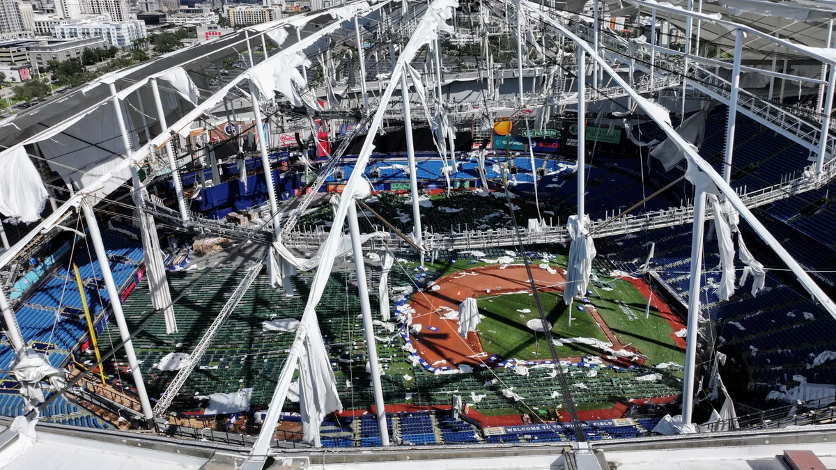 An aerial view of a stadium dome torn apart revealing the field below.