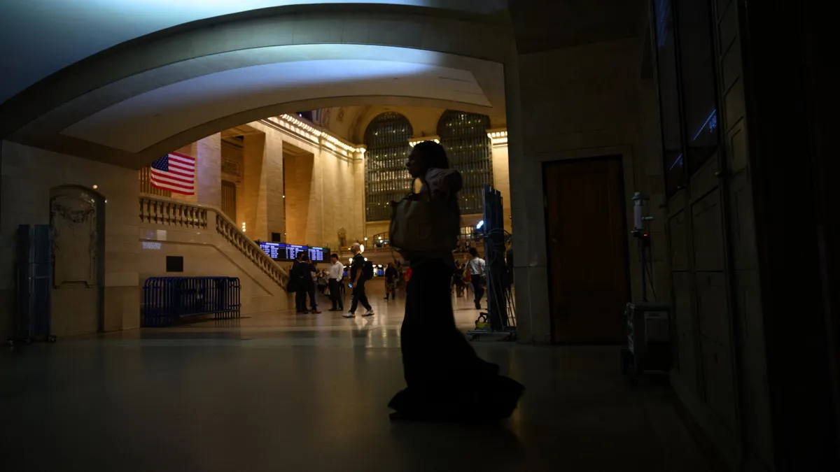 People walk through an area illuminated by a portable floor light in Grand Central Terminal following a power outage.