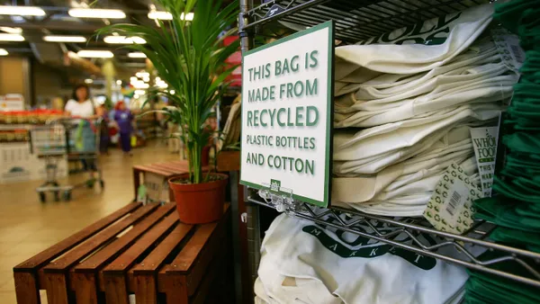 Tote bags for sale at Whole Foods. A sign says the bags are made from recycled materials.