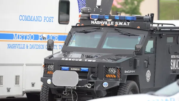 A black truck that says "Nashville S.W.A.T" parked in front of a white van that says "Metro Police."