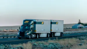An ABF Freight System semi-truck with a double combination with fields in the foreground and background.